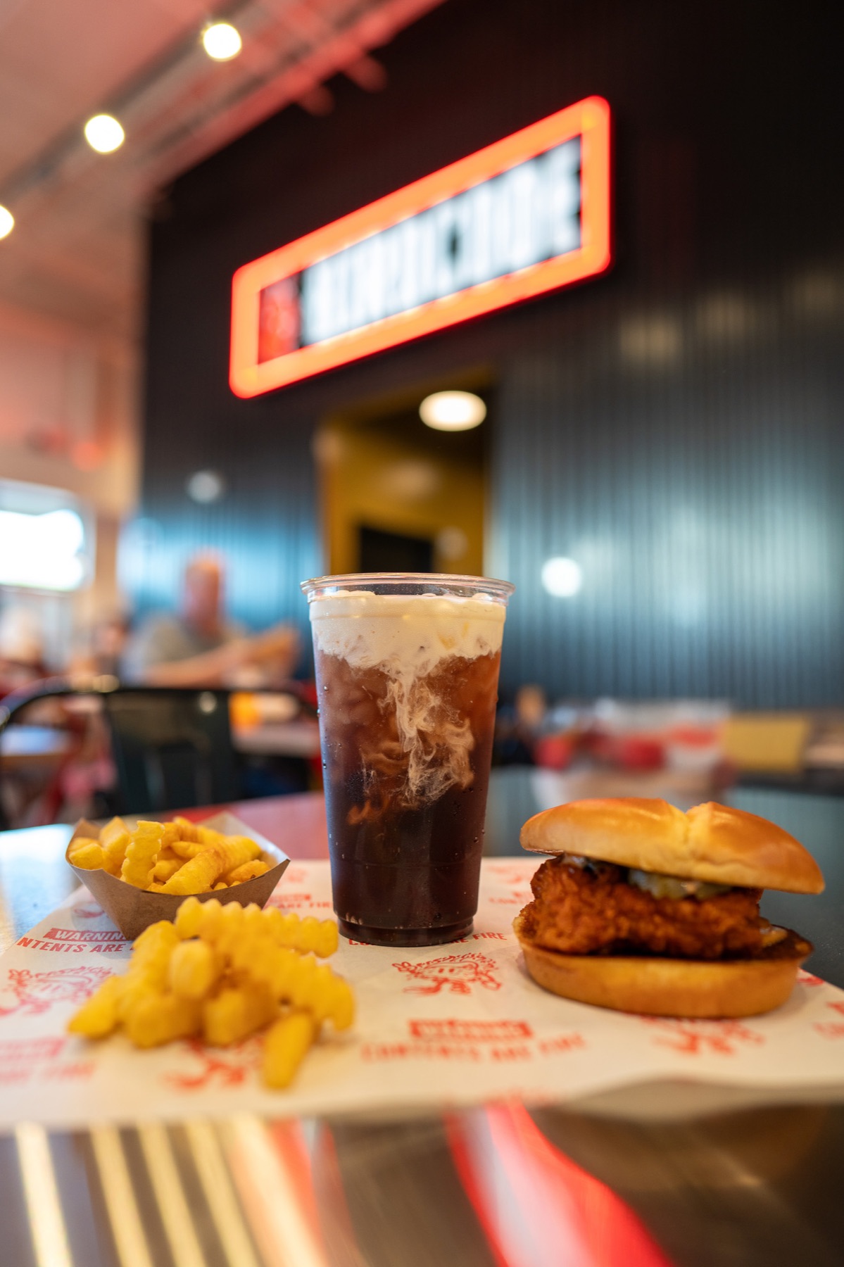 Birdcode sandwich, fries, and drink inside a restaurant